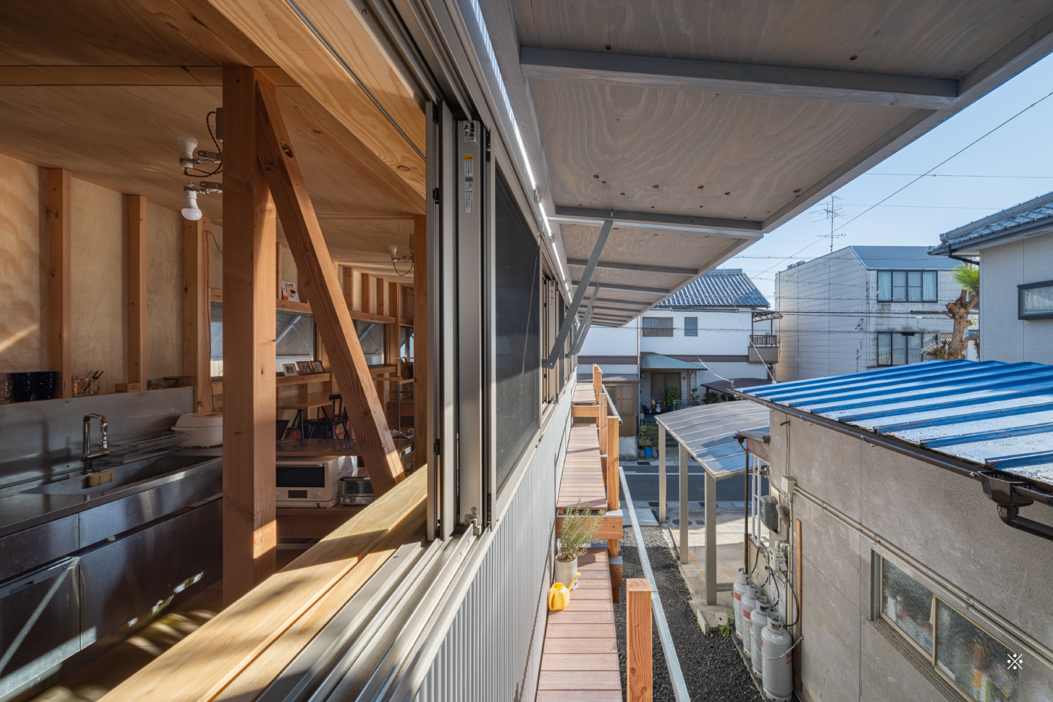 ２階の窓辺の風景。跳ね上げ式の建具とスライド式の窓が開いて室内風景が覗いている。