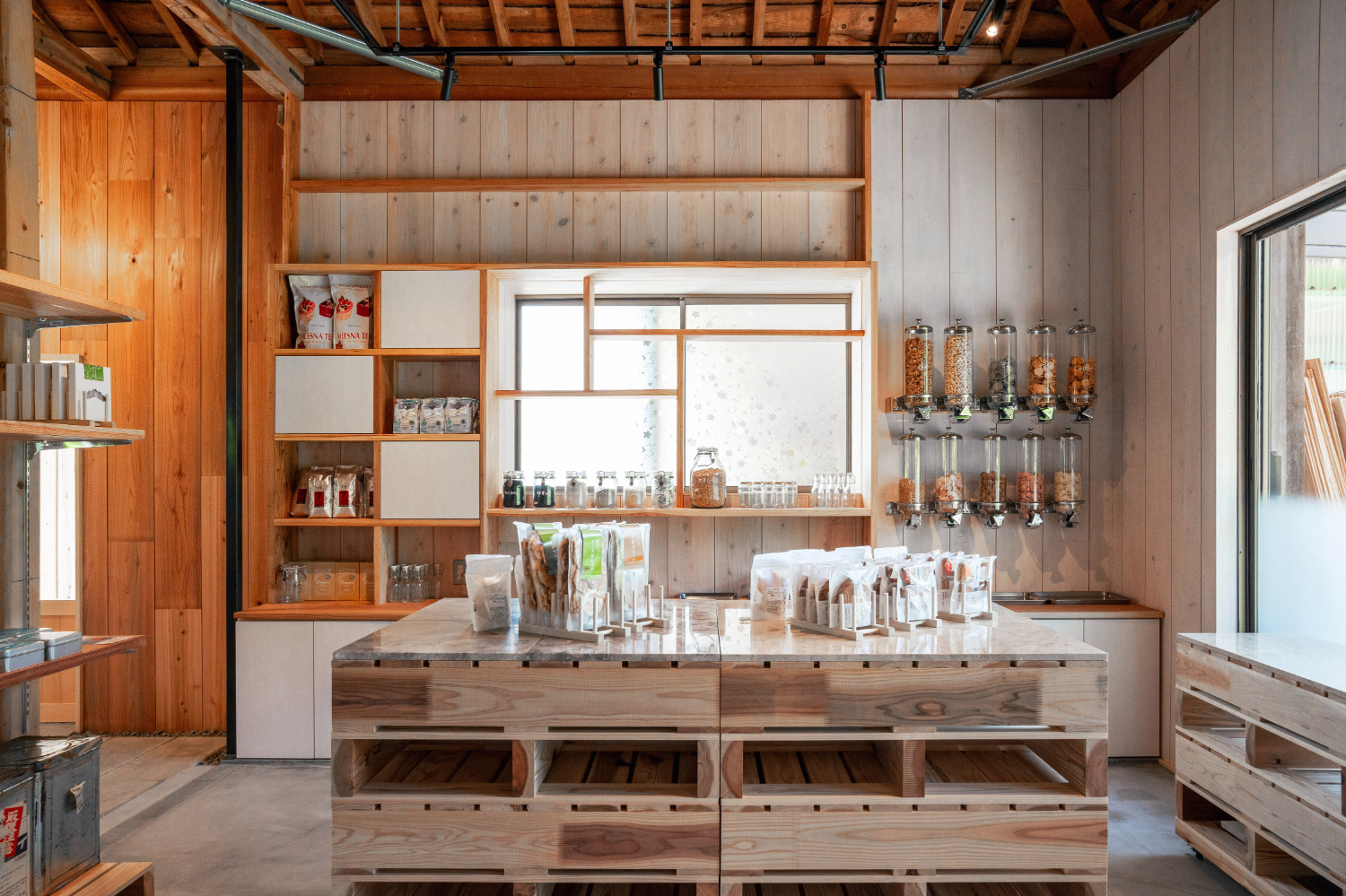 物販ブースのアップ風景。壁は木質で白い塗料が薄く塗られている。壁面の窓から光が差し込んでいる。